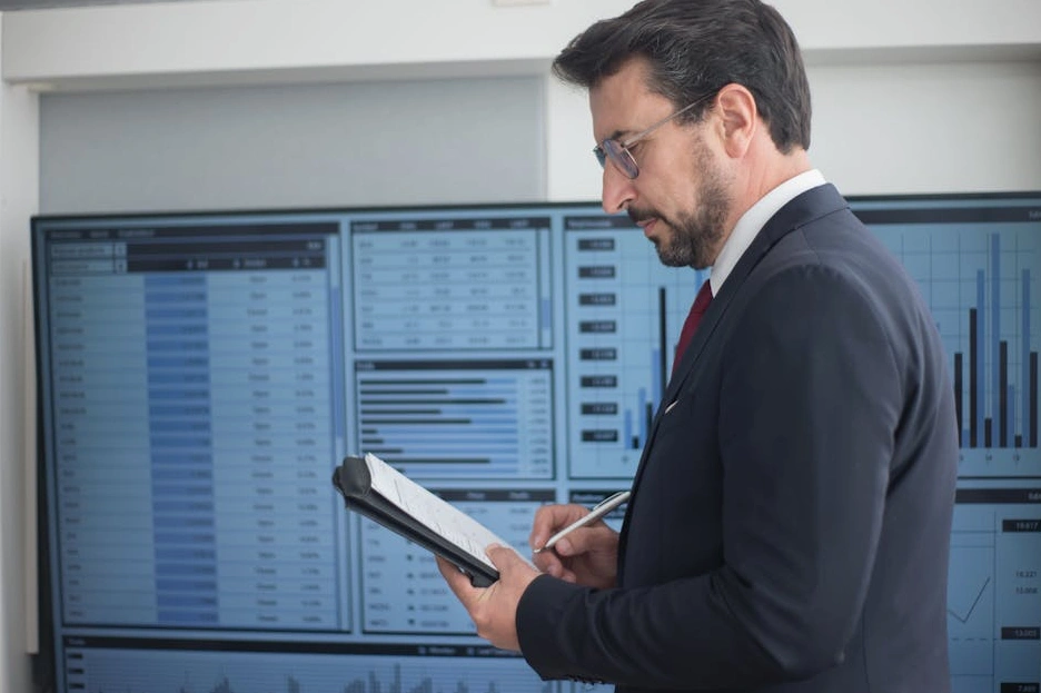 Osoba soustředěně analyzuje finanční grafy na tabletu.